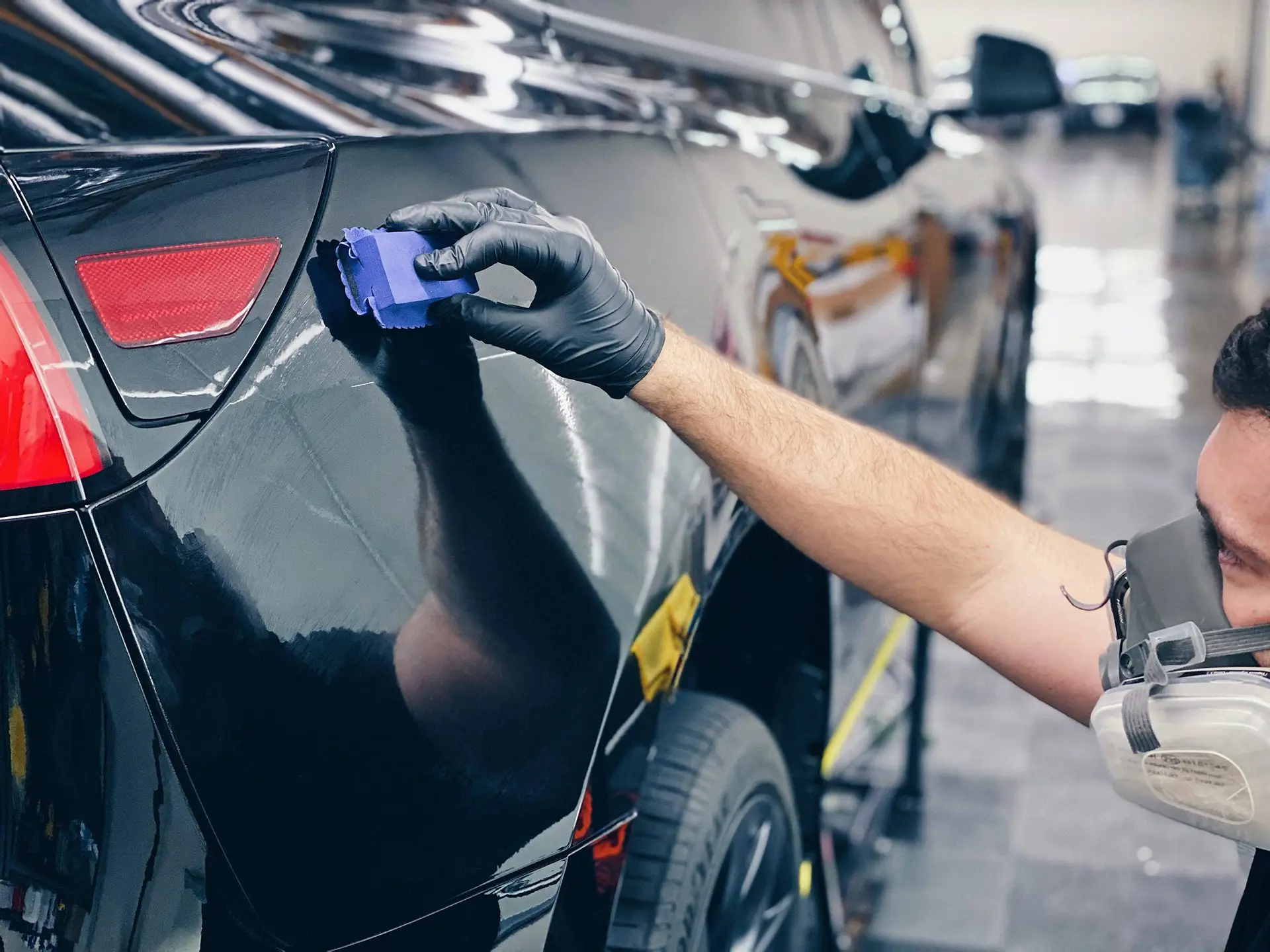 Gloved hand applying Gtechniq EXO ceramic coating to a black Tesla Model Y