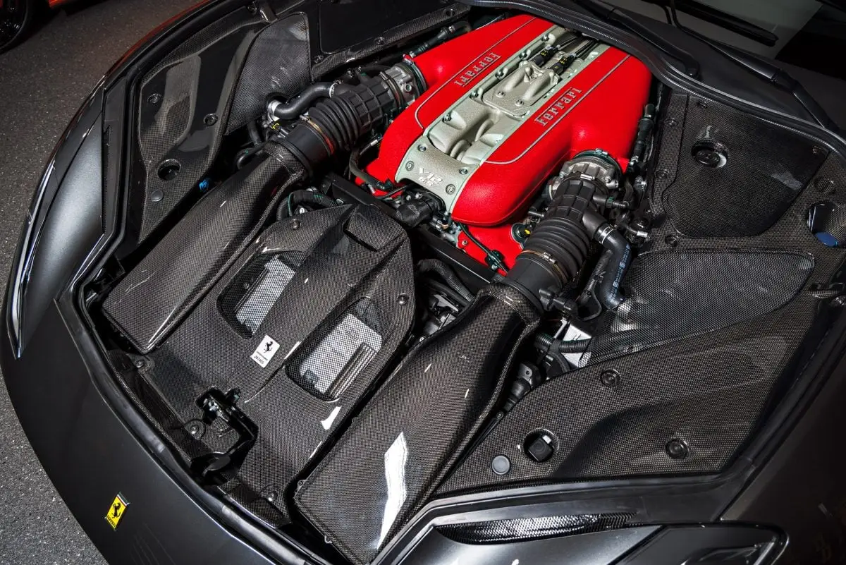 Ferrari 812 Superfast V12 engine bay with red intake plenum and carbon panels after an ST6 engine detail