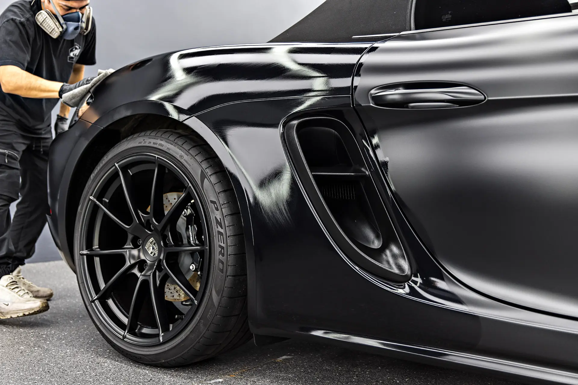 Technician wiping ceramic coating on a black Porsche