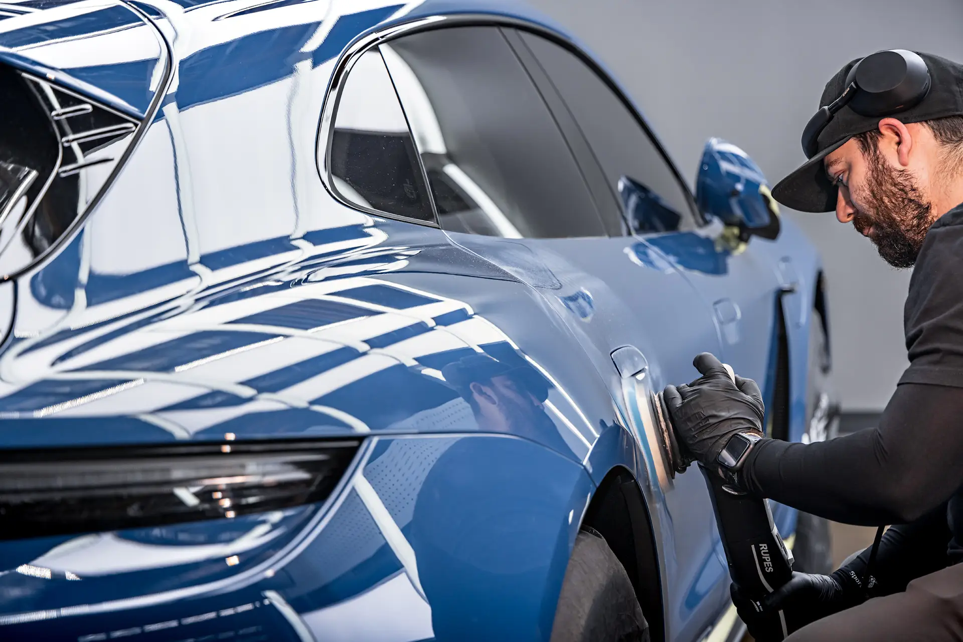ST6 technician machine polishing a blue Porsche