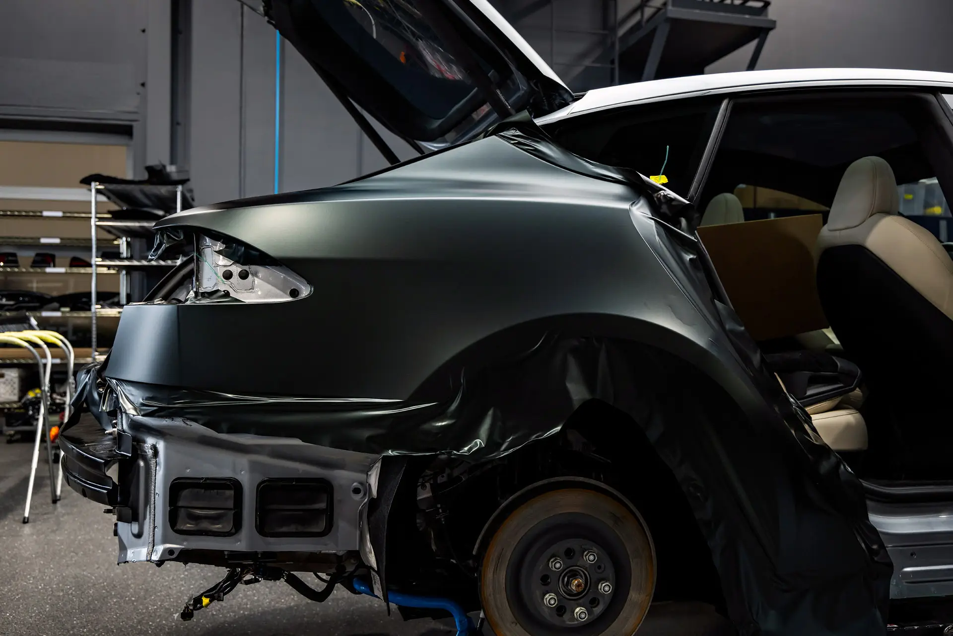 Front corner of a Tesla in matte grey colour-change vinyl with trim removed for wrapping