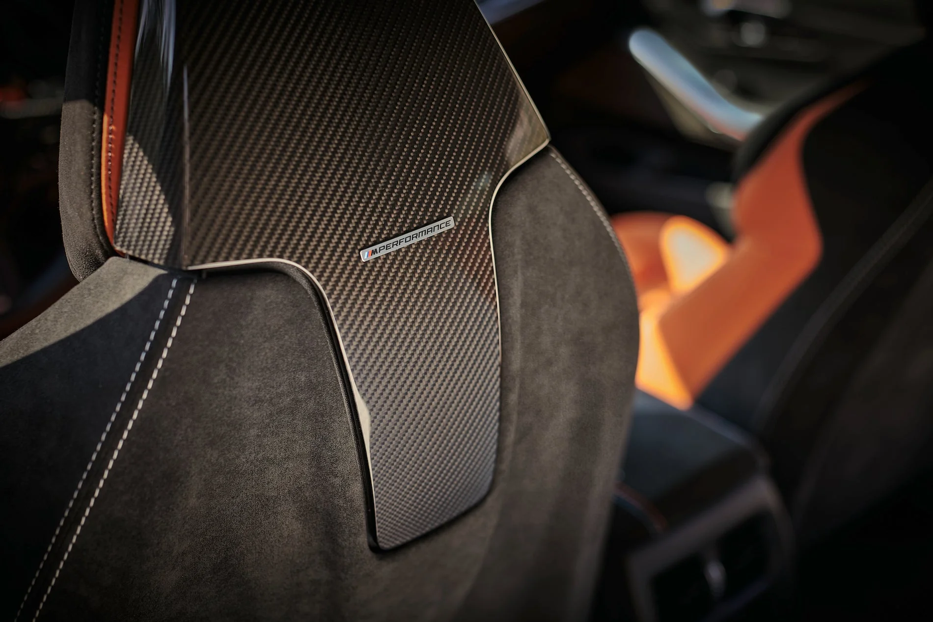 Alcantara and carbon-fibre bucket seat with orange accents in a dark cabin