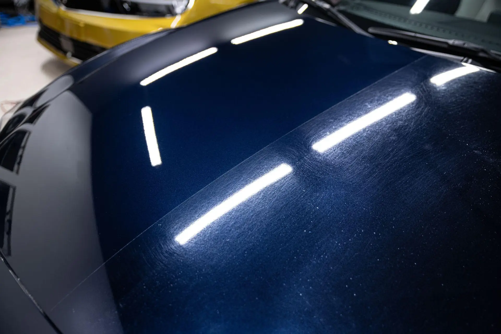 Blue BMW hood half polished, swirled on one side and corrected on the other