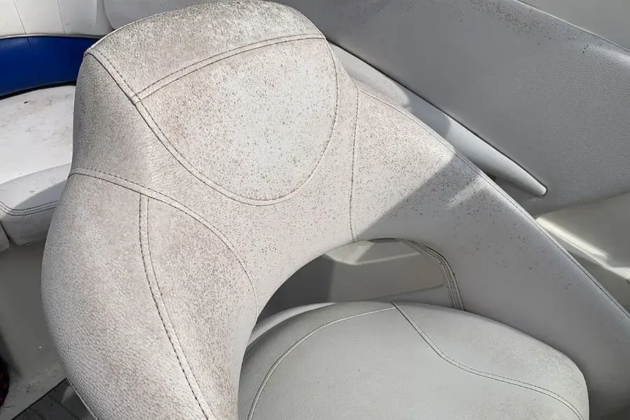 Grey and white helm seat with mottled mildew staining before cleaning