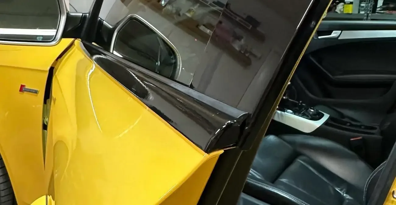 Open door of a yellow car showing blacked-out window trim and a black interior