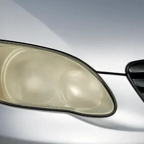 Headlight on a silver car fogged opaque yellow, the reflectors barely visible through the oxidised lens