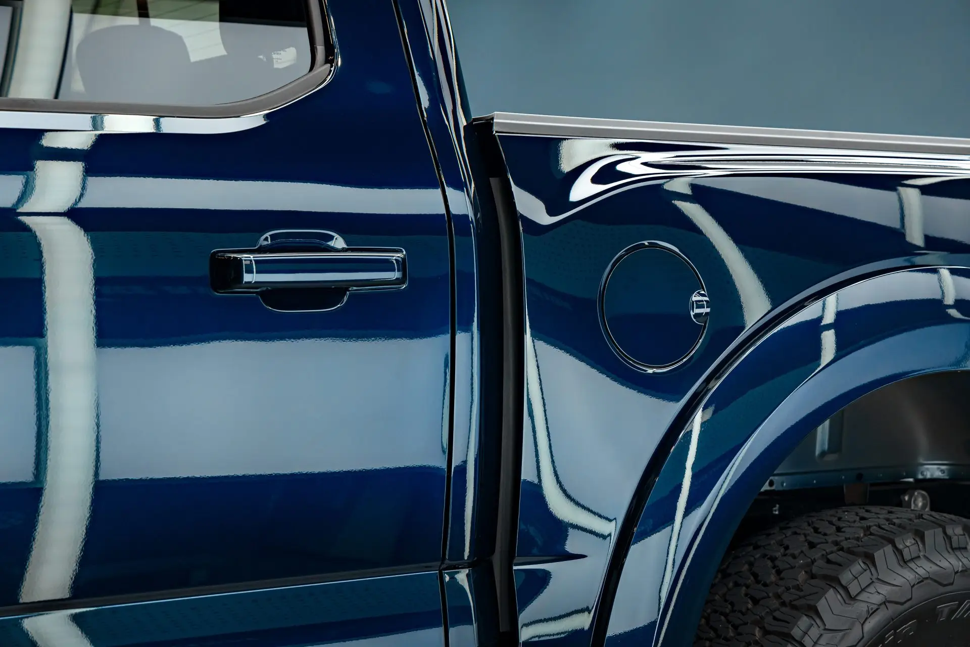 Door handle and rear wheel arch of a dark blue Ford Raptor with a mirror-gloss finish