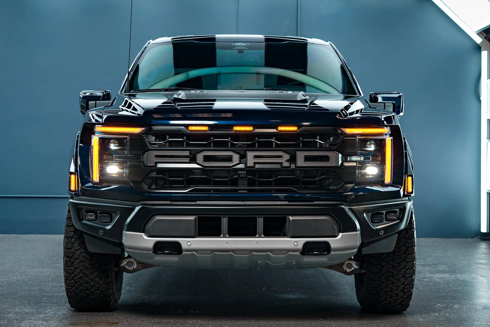 Front grille and lit amber marker lights of a dark Ford F-150 Raptor at ST6 Detailers in Colorado Springs