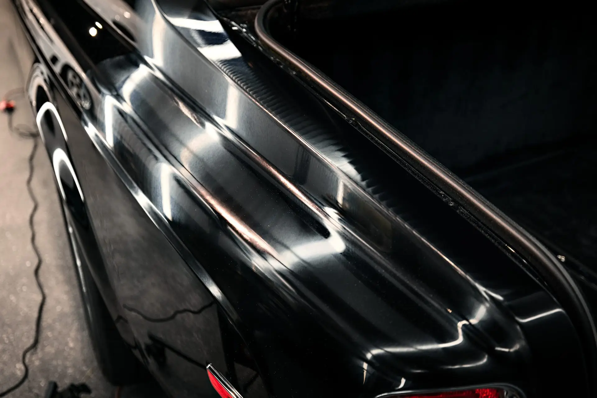 Sharp overhead light reflections running down corrected black paint