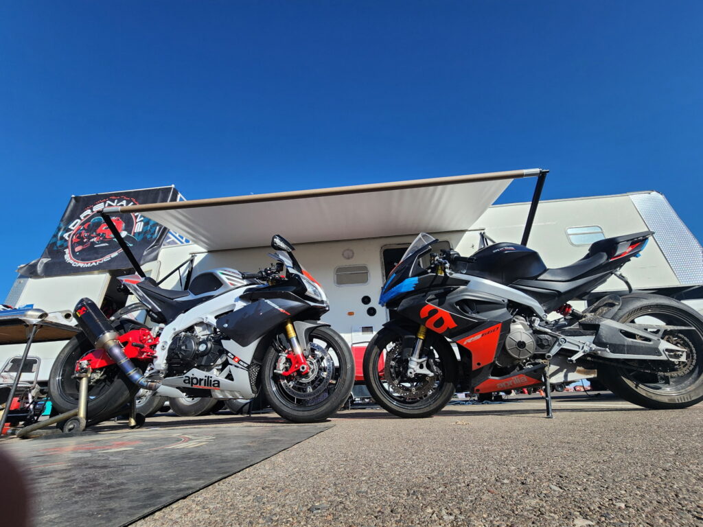 Aprilia RSV4 and Aprilia RS 660 superbikes parked side by side under an RV awning
