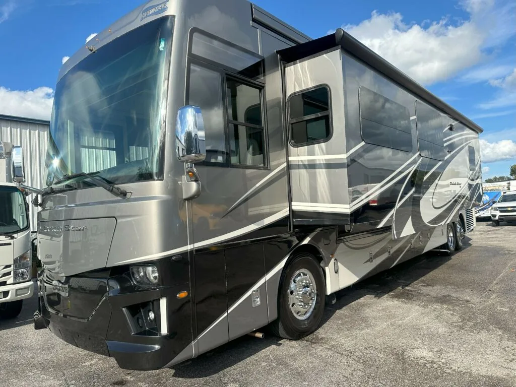 Champagne and grey Class A diesel motorhome with a slide-out, parked in a lot