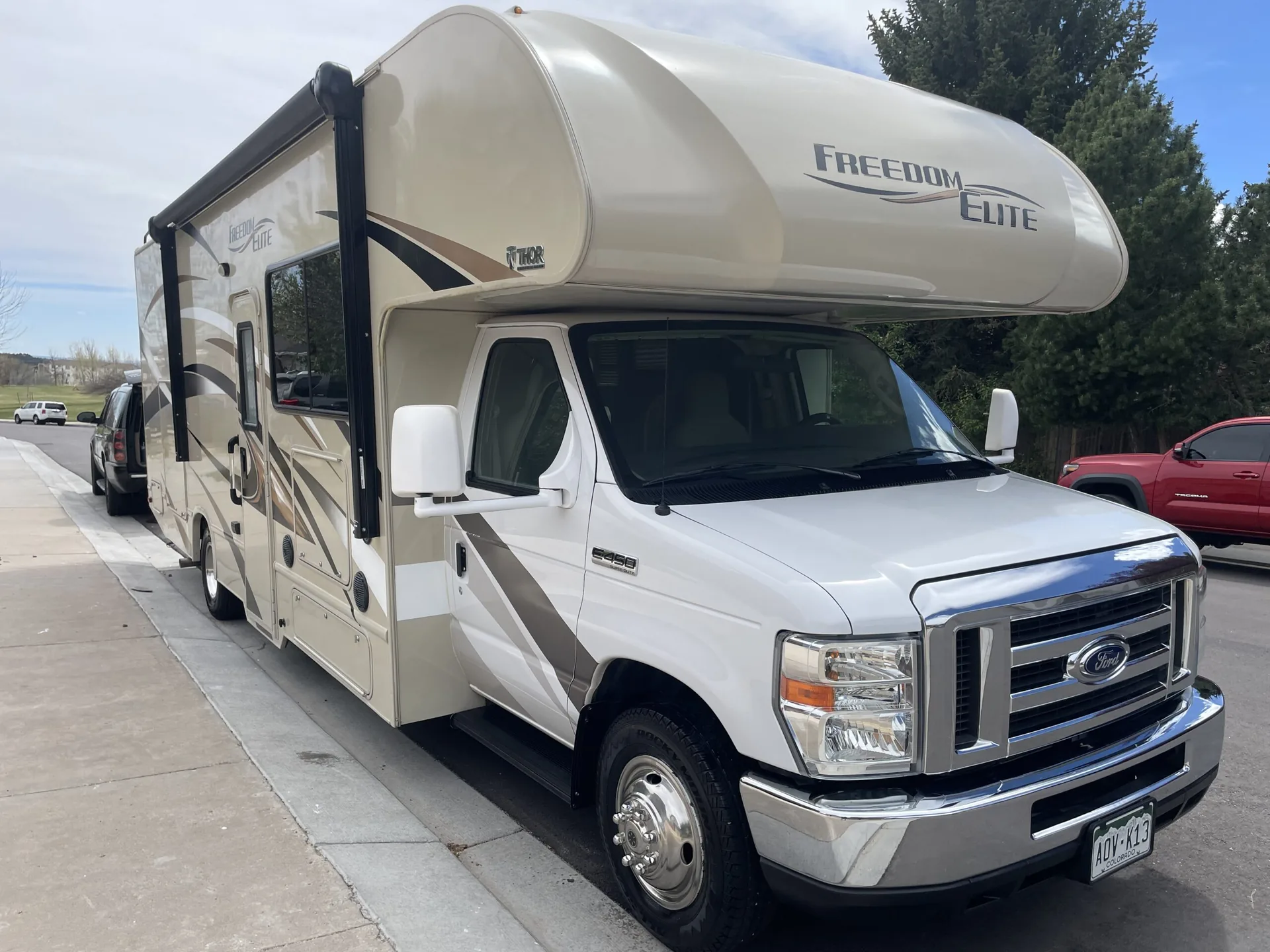 Tan and white Freedom Elite Class C motorhome on a Ford chassis parked at the kerb
