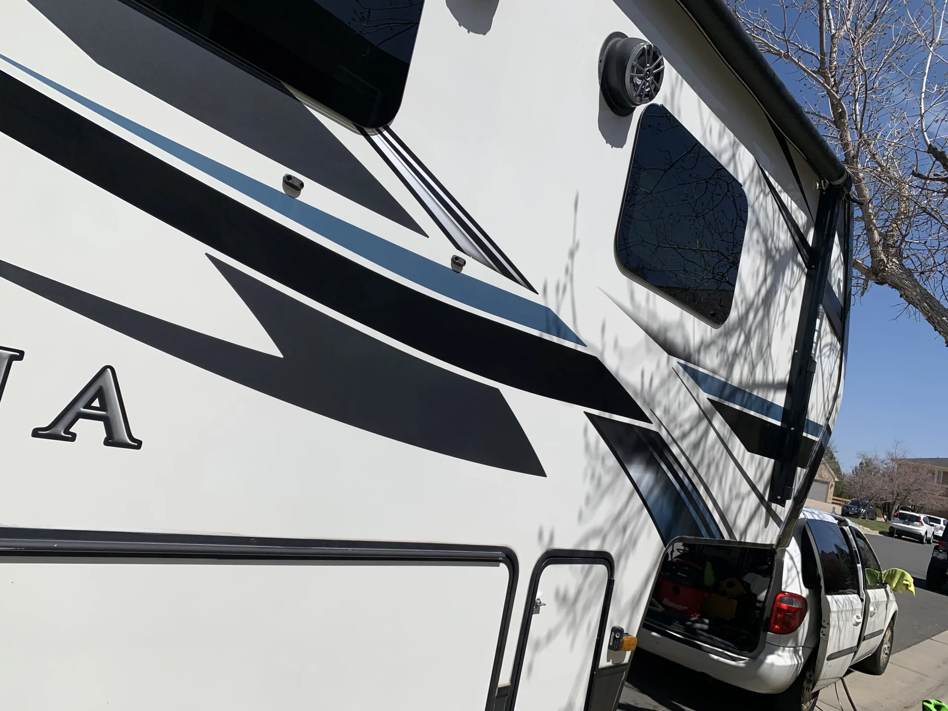 Side of a white Montana fifth-wheel with black swoosh graphics, freshly polished