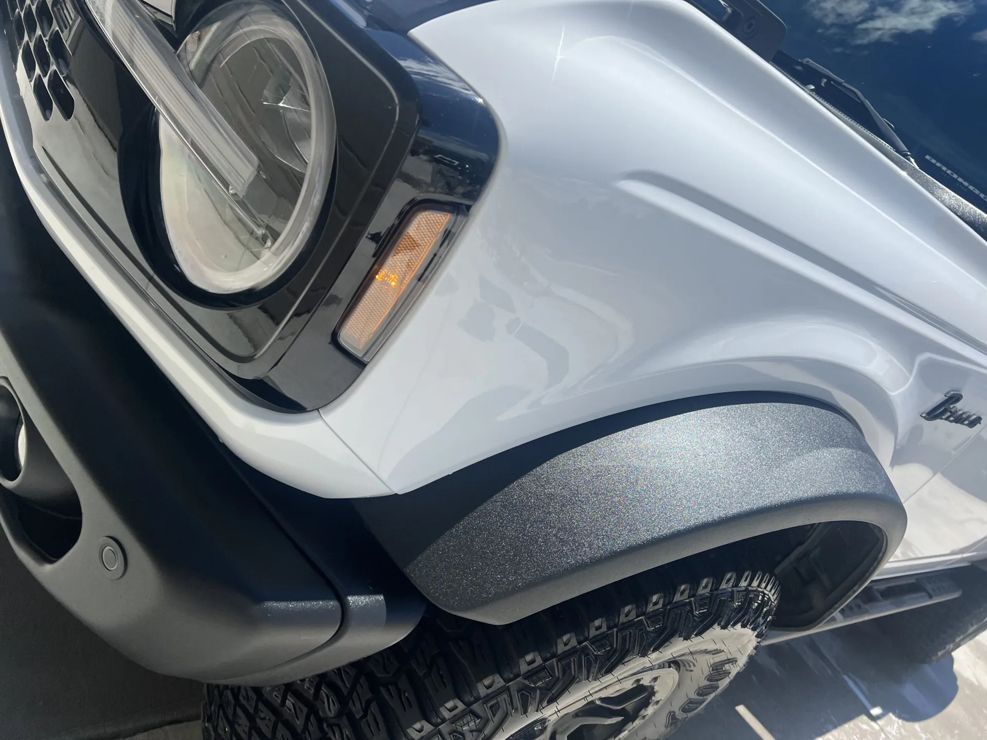 Close-up of the front fender, headlight and textured wheel-arch flare on a white Ford Bronco detailed by ST6 Detailers