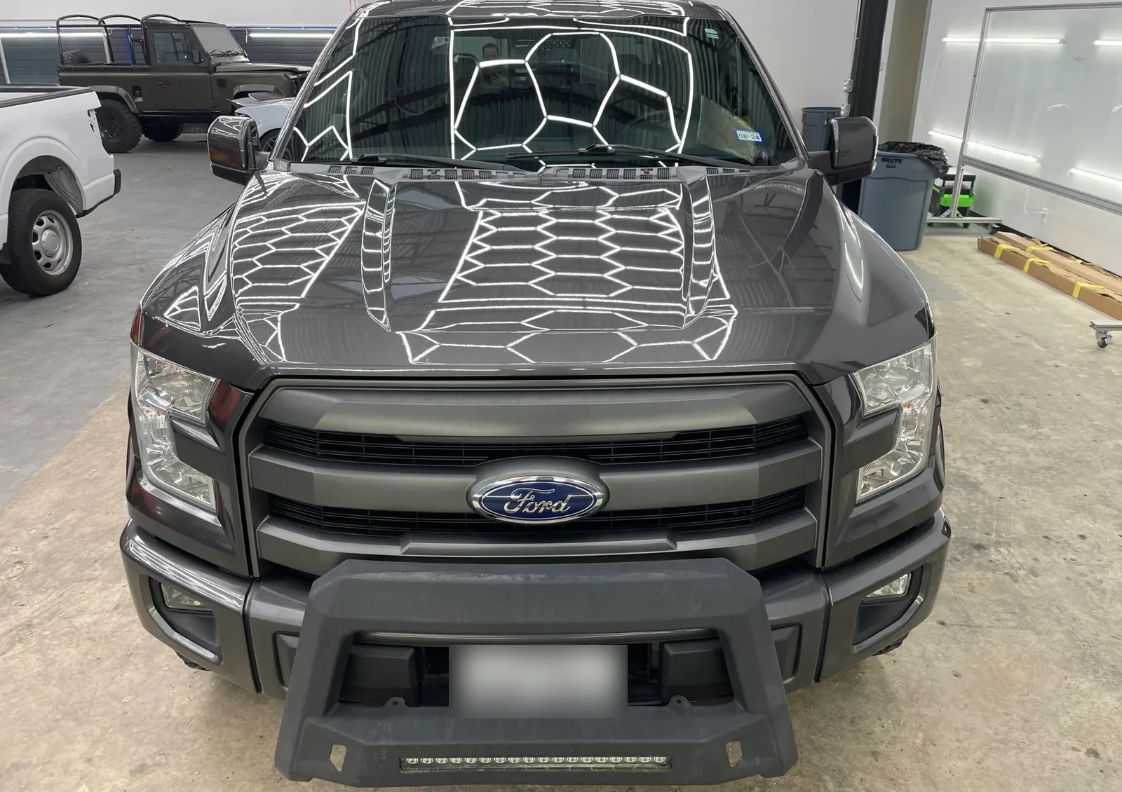 Gray Ford F-150 hood reflecting hexagon shop lights after paint correction