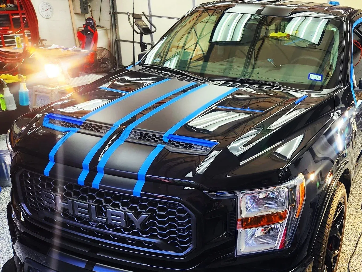 Black Shelby F-150 with blue tape on stripes and trim before paint correction