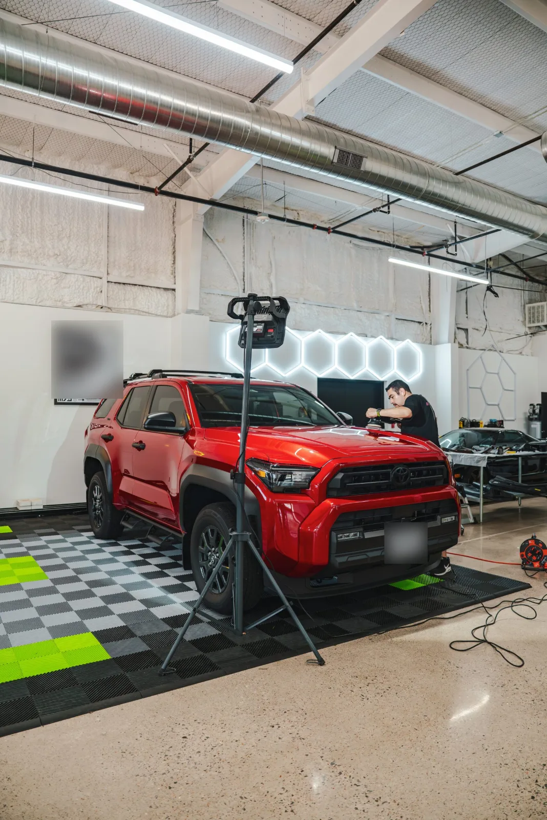 Red Toyota 4Runner being machine polished under inspection lights