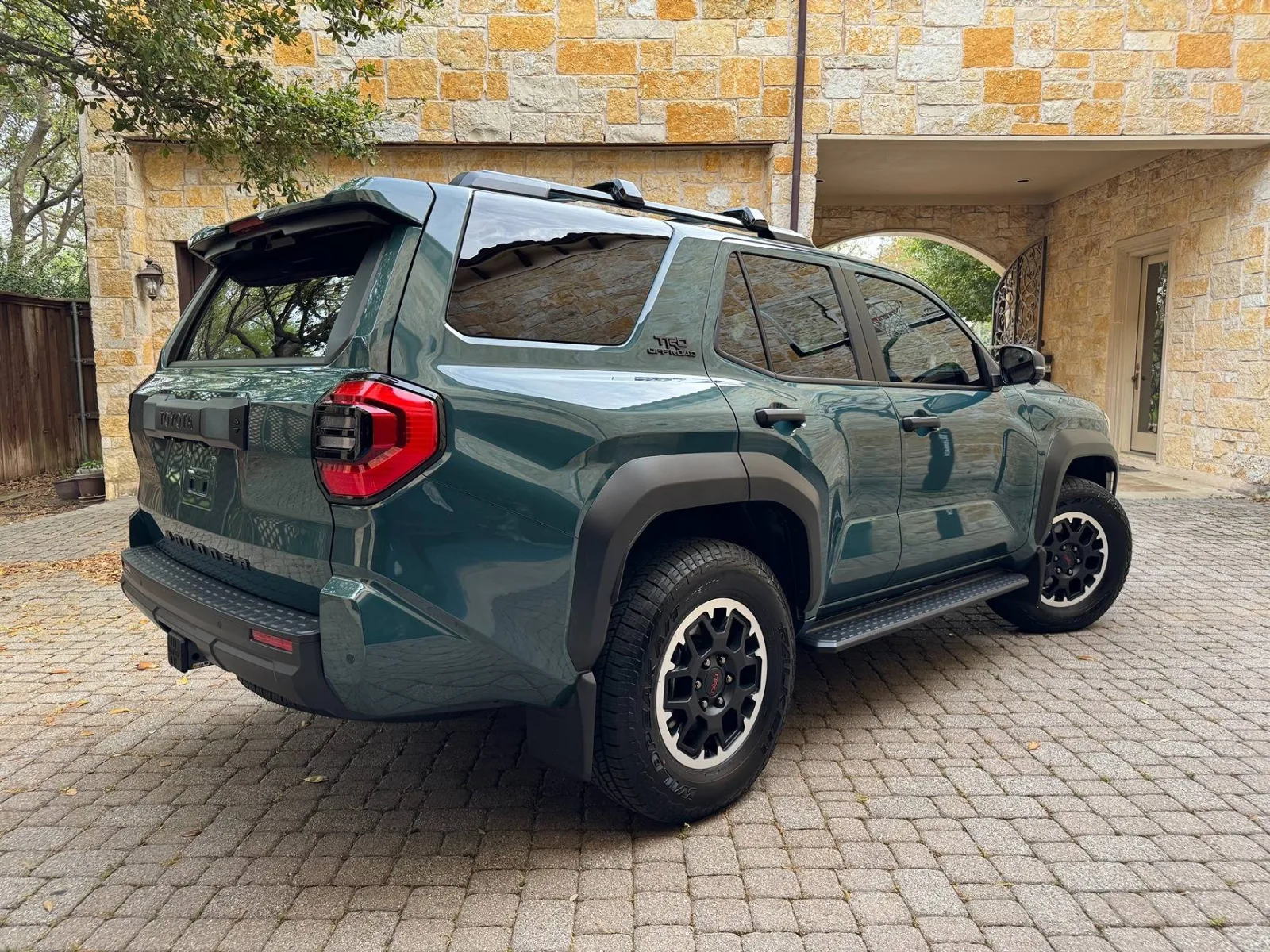 Green Toyota 4Runner TRD Off-Road with glossy corrected paint reflecting a stone wall